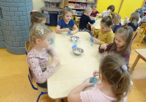 Dzieci barwią roztwór z soli na niebiesko.